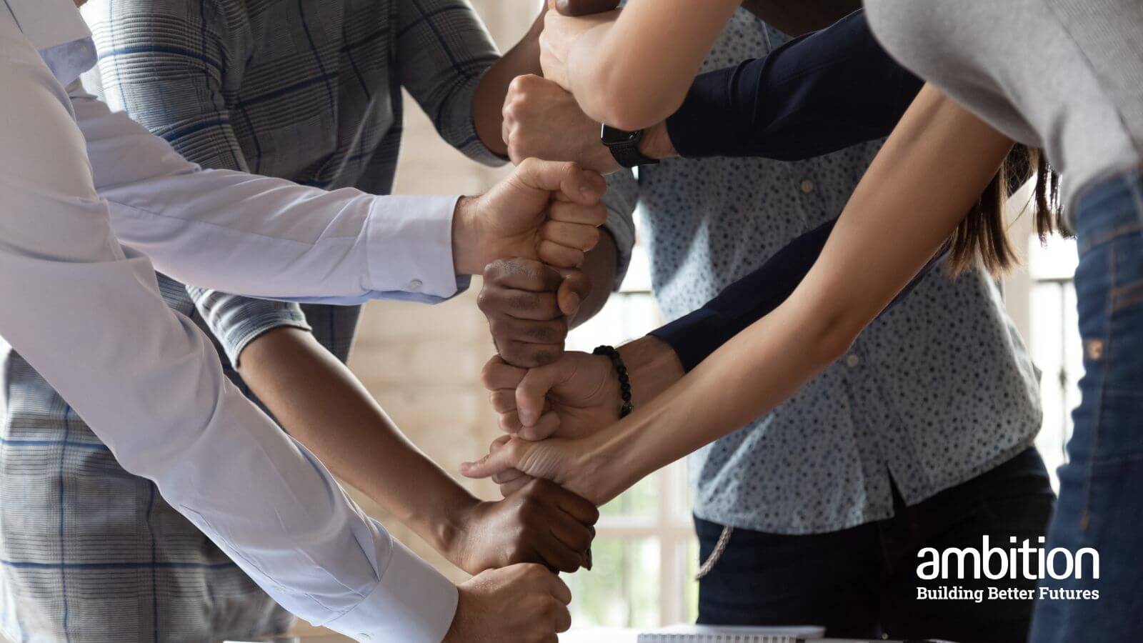 Arms of a team of people building a tower with their fists